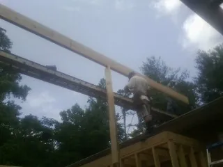 Carpenter setting a ridge beam over a new addition frame — Ice Dam Removal by Roofing Brothers in Kittrell