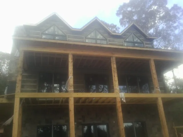 Dormers and porch framing on a large log home under construction — Roof Coating work by our crew in Kittrell