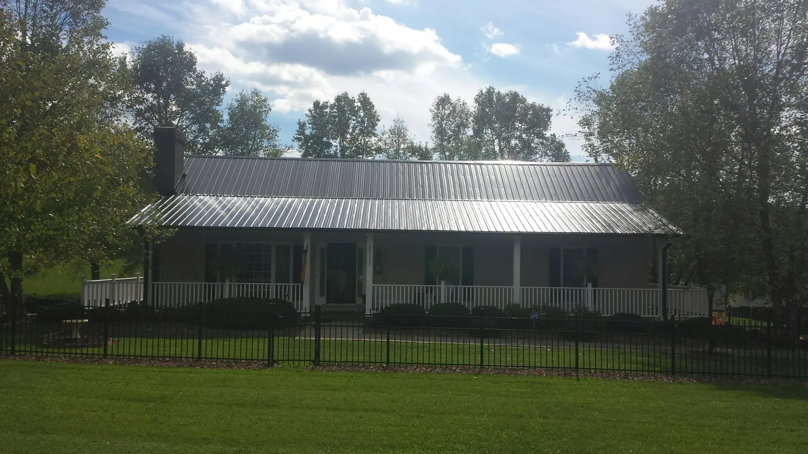 Gray metal roof on a brick ranch with a full width front porch — Gutter Guard Installation work by our crew in Kittrell