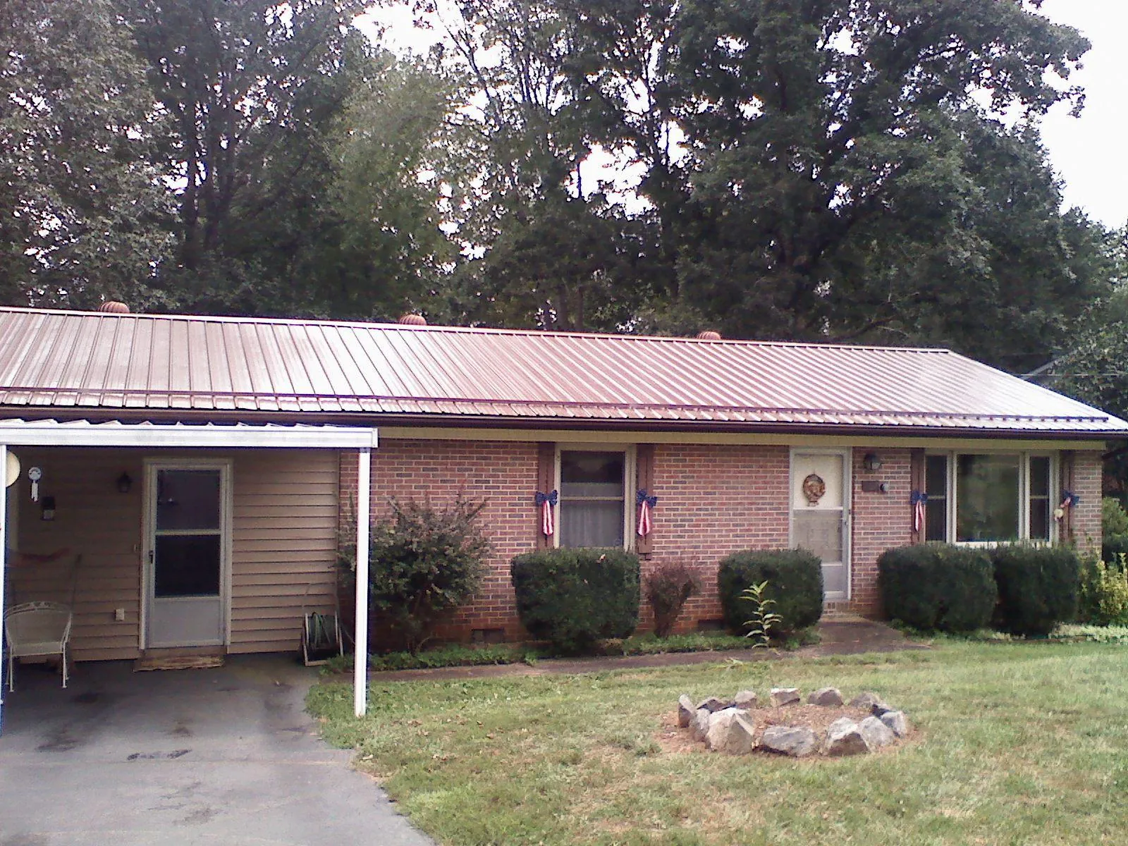 Bronze metal roof and carport on a brick ranch home — Roof Repair work by our crew in Kittrell